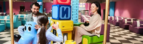 A child happily plays with a toy in a cozy restaurant while their family enjoys a relaxing weekend outing. — Stock Photo