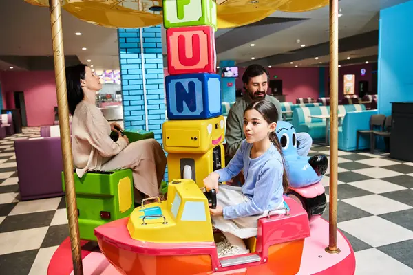 Uma família alegre gira em um carrossel dentro de uma loja de brinquedos em uma zona de jogos shoppings durante um passeio de fim de semana. — Fotografia de Stock