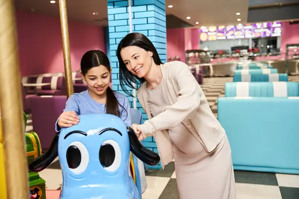 Uma mãe e seu filho compartilham um momento de alegria brincando com um carrossel de brinquedo colorido em uma zona de jogos de shoppings em um fim de semana.. — Fotografia de Stock