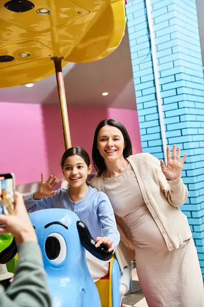 A joyful mother and child capturing a moment while riding a toy carousel in a malls gaming zone during the weekend. — Stock Photo