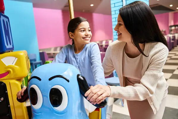 A woman and child laughing as they play with a toy carousel in a vibrant toy store at a bustling mall on the weekend. — Stock Photo