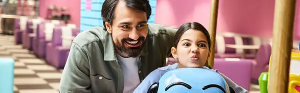 A father and child happily sitting on a toy in a childrens play area inside a mall during the weekend. — Stock Photo