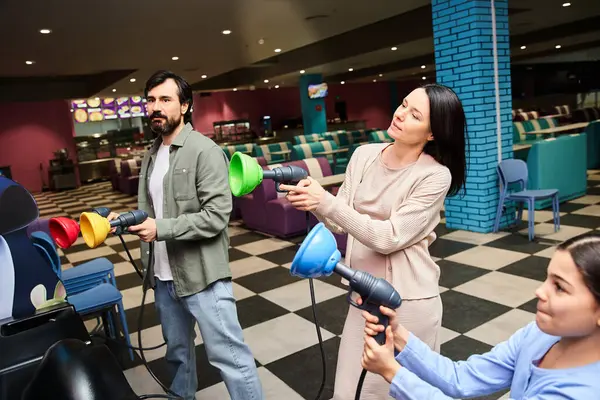 A happy family enjoying a game in a vibrant, bustling bowling alley on a weekend. — Stock Photo