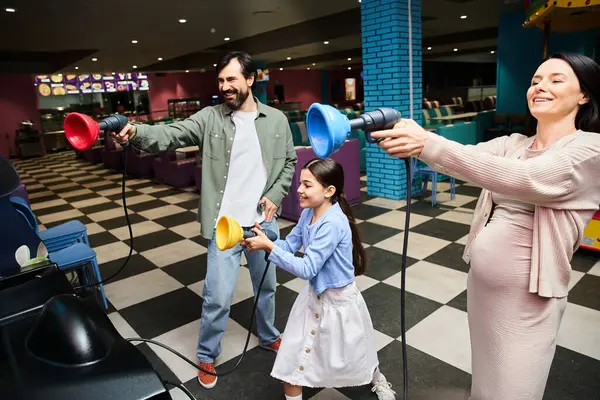 Uma família feliz, pais e filhos, imersos em animada competição de jogos na zona de jogos dos shoppings em um fim de semana. — Fotografia de Stock