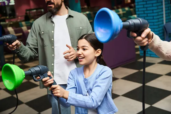 Une famille joyeuse joue à des jeux ensemble dans l'aire de jeux animée d'une piste de bowling pendant une sortie de week-end. — Photo de stock