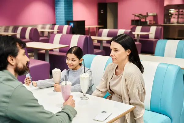 A happy family enjoys quality time at a modern diner during the weekend, chatting and sharing a drinks together. — Stock Photo