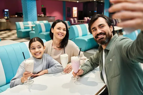 A happy family captures a moment, taking a selfie together at a diner during a weekend outing. — Stock Photo