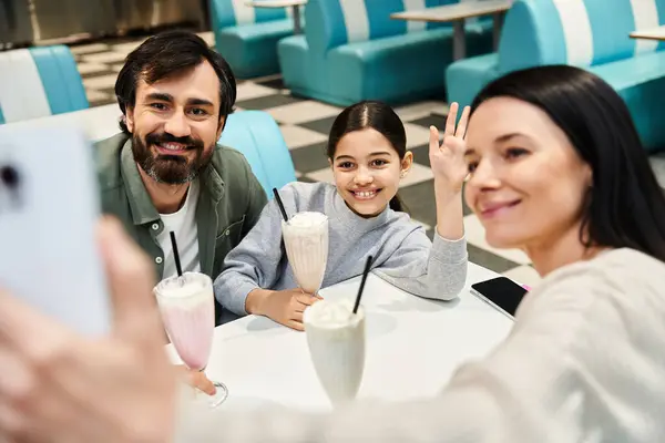 A joyful family captures a moment together, smiling as they take a selfie in a charming retro diner during their weekend outing. — Stock Photo