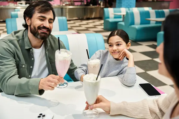 Uma família feliz gosta de milkshakes em um restaurante durante o fim de semana, rindo e compartilhando tempo de qualidade juntos. — Fotografia de Stock