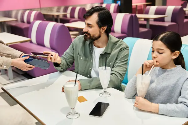Famiglia che si gode un pasto insieme in un ristorante, padre che paga con carta di credito nel caffè — Foto stock
