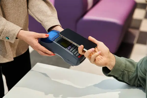 A man happily hands a credit card to another person in a modern setting, symbolizing a gesture of generosity and trust. — Stock Photo