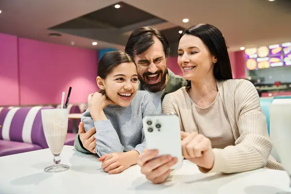 A joyful family gathers at a restaurant, happily taking a selfie together to preserve their weekend memories. — Stock Photo
