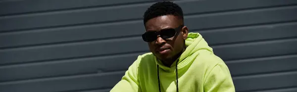 A fashionable African American man wearing a green hoodie and sunglasses. — Stock Photo