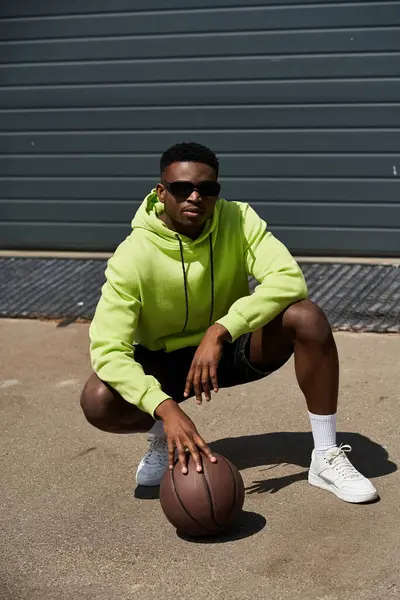 Stylish African American man crouches with basketball. — Stock Photo