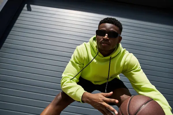 African American man in green hoodie holds basketball. — Stock Photo