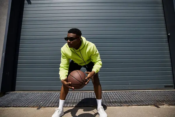 Handsome man in yellow hoodie with basketball. — Stock Photo