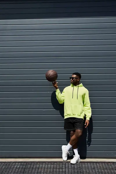 Elegante hombre afroamericano sosteniendo baloncesto por garaje. - foto de stock