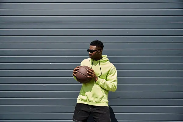 Young man in green hoodie holding basketball. — Stock Photo