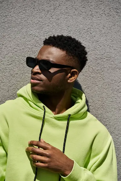 Handsome African American man in trendy lime green hoodie and sunglasses. — Stock Photo