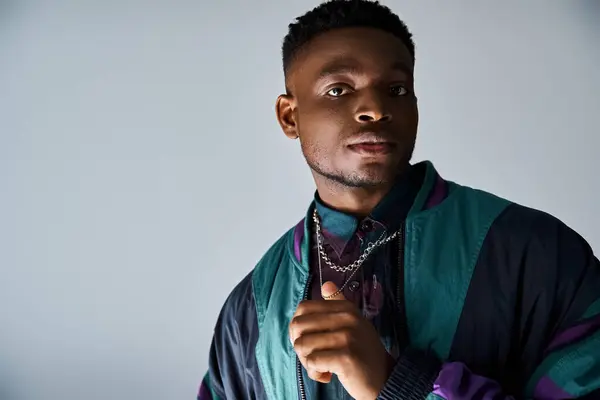 A fashionable young African American man posing confidently in a blue and purple jacket. — Stock Photo