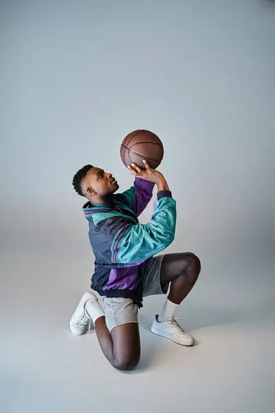 Um jogador de basquete afro-americano elegante se agacha para pegar uma bola. — Fotografia de Stock