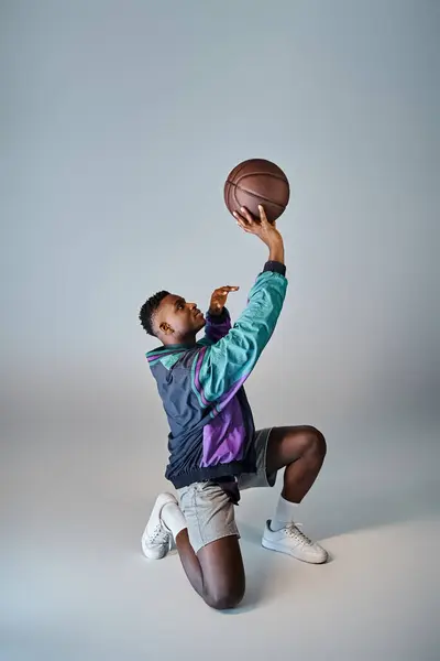 Ein eleganter afroamerikanischer Basketballspieler duckt sich, um den Ball zu fangen. — Stockfoto