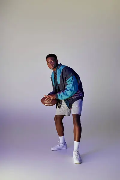 Handsome African American man poses with a football against a white backdrop. — Stock Photo