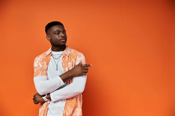 Stylish African American man in orange shirt posing against matching background. — Stock Photo