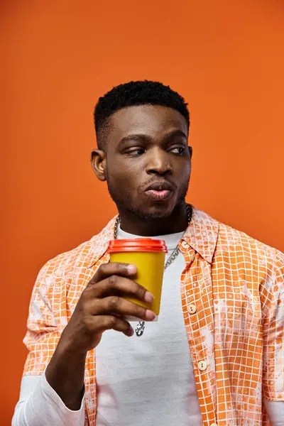 Handsome man in orange shirt enjoying coffee — Stock Photo