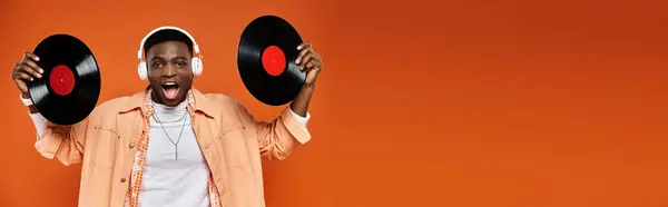 Man holding two vinyl records against an orange backdrop. — Stock Photo