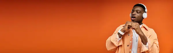 Handsome man in orange shirt dancing and listening music. — Stock Photo