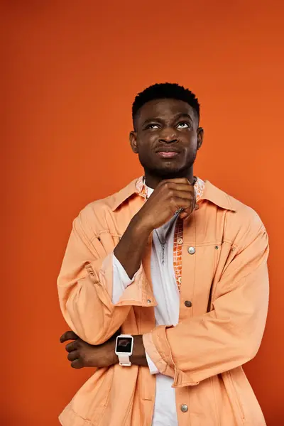 Handsome man in orange jacket striking a thoughtful pose. — Stock Photo