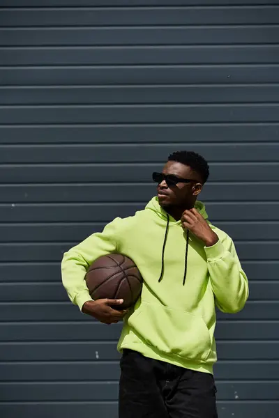 Schöner Mann in grünem Kapuzenpulli zeigt Basketball-Fähigkeiten. — Stockfoto