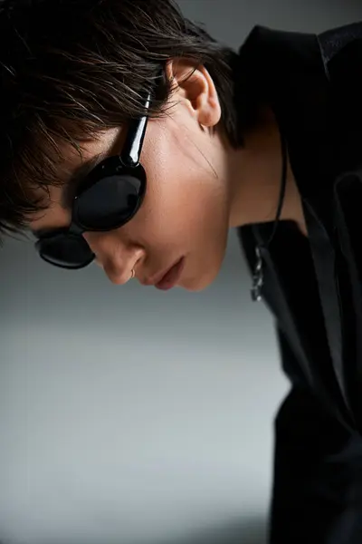 A woman in black sunglasses leaning against a wall. — Stock Photo