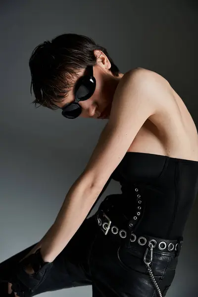 Young woman strikes a pose in trendy black leather pants with sunglasses on — стоковое фото
