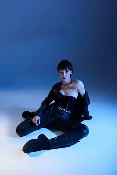 A beautiful young woman poses actively in stunning black leather attire. — Stock Photo