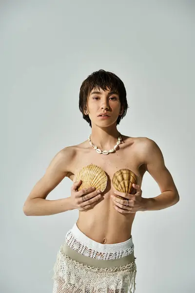 A beautiful woman in stylish attire gently cradling a shell on her chest. — Stockfoto