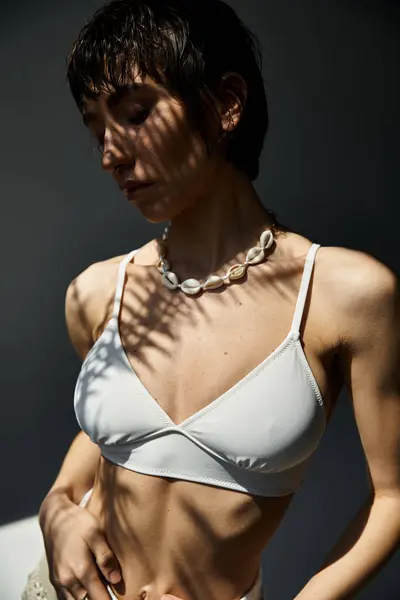 A young woman exudes elegance in a white bikini as she poses actively. — Stock Photo