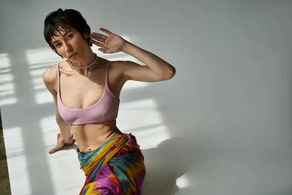 A young woman poses in a lively, fashionable top against a white backdrop. — Stock Photo