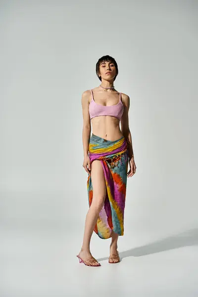 A vibrant young woman in a bikini striking a pose in a colorful skirt. — Stock Photo