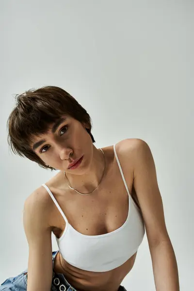 Stylish young woman posing in a white bra top on white backdrop. — Stock Photo