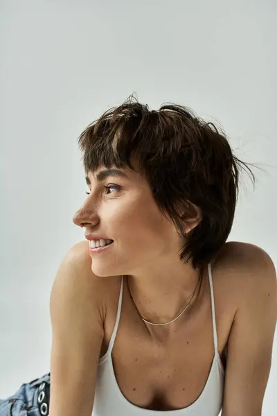 Stylish young woman in white tank top lays gracefully on floor. — Stockfoto