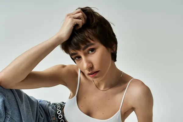 Stylish young woman posing confidently in white tank top and jeans. — Stock Photo