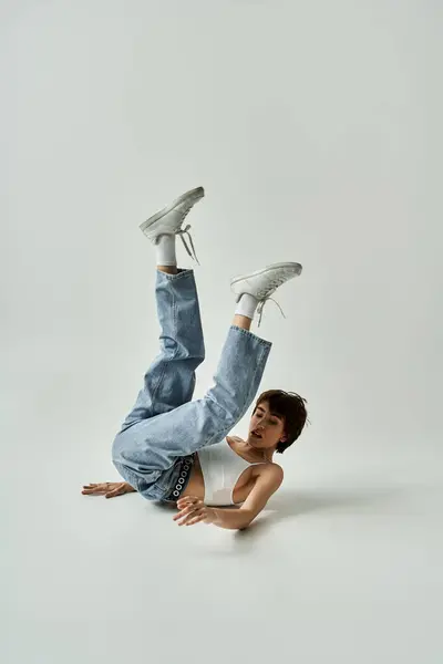 Young woman executing breakdance moves energetically on white background. — стокове фото