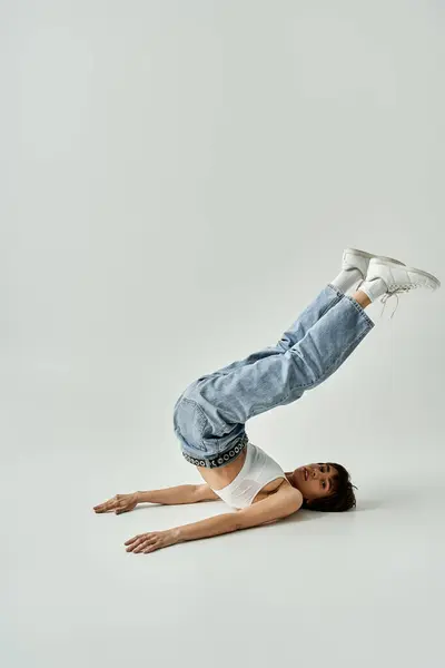 Stylish young woman doing a handstand on white background. — стоковое фото