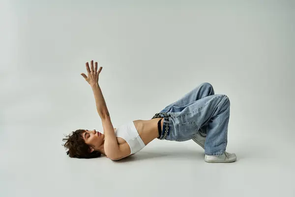 A beautiful young woman laying on her back in stylish attire on a white background. — Stockfoto