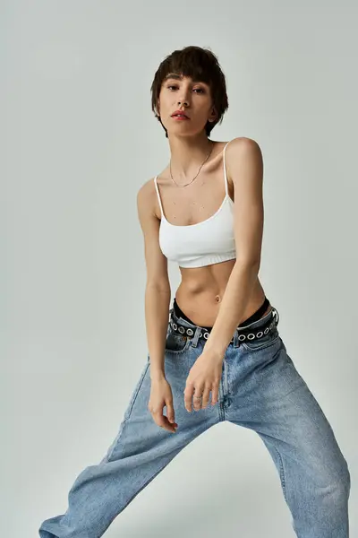 Stylish young woman in jeans and white top striking a pose. — Stock Photo