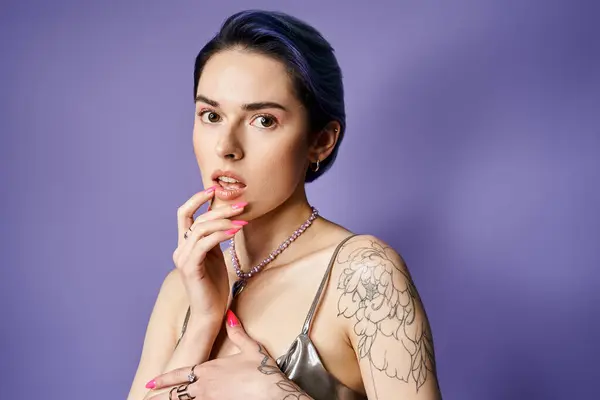 A woman, adorned with tattoos on her arms and chest, exudes confidence and individuality in a studio setting. — Photo de stock