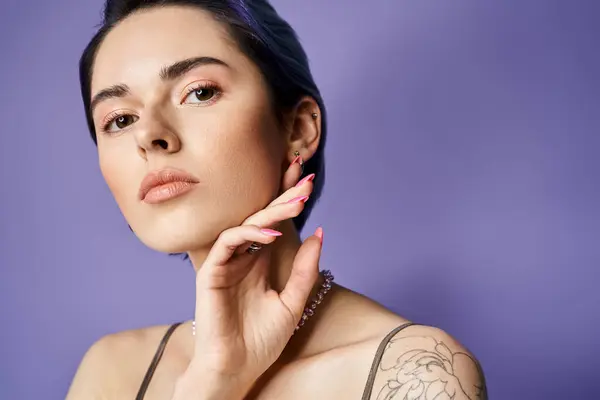 A young woman with short blue hair showcases her arm tattoo while posing in a silver party dress in a studio setting. — Stock Photo