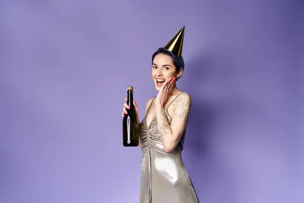 Young woman with short blue hair, wearing a silver party dress and hat, holding a champagne bottle. — Fotografia de Stock